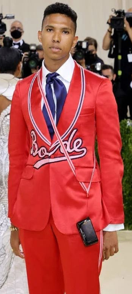 A fashion model Tyler Mitchell wearing a red suit and a woman in a white dress at a Quinceanera