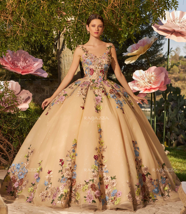 A woman in a Quinceanera gown standing in front of flowers.