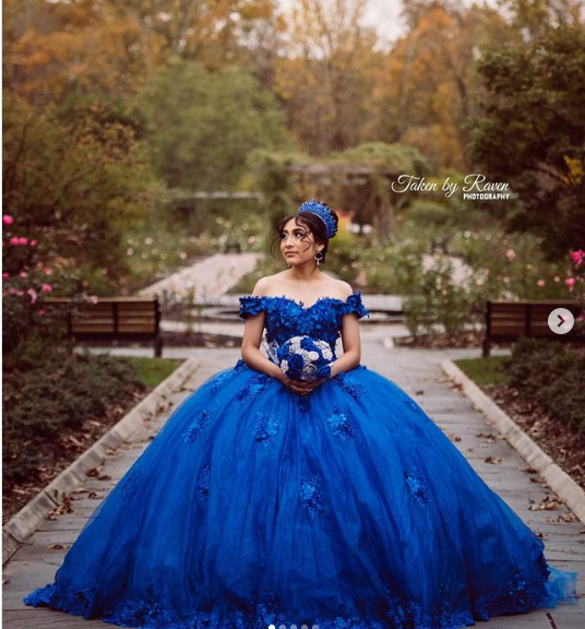 A woman in a blue Quinceanera gown posing for a picture