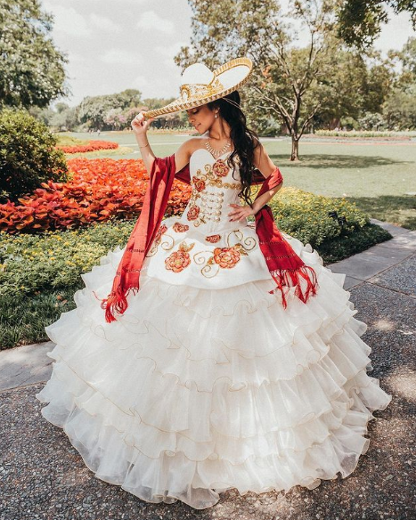 A Quinceanera gown: a woman wearing a white dress and a red cape