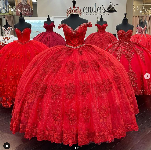 Three red Quinceañera dresses on display in a store