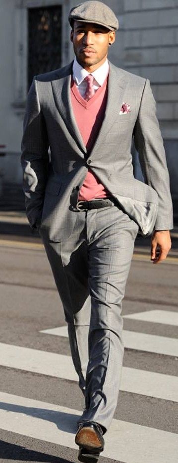 A man wearing a grey pink combination suit and hat, crossing a street