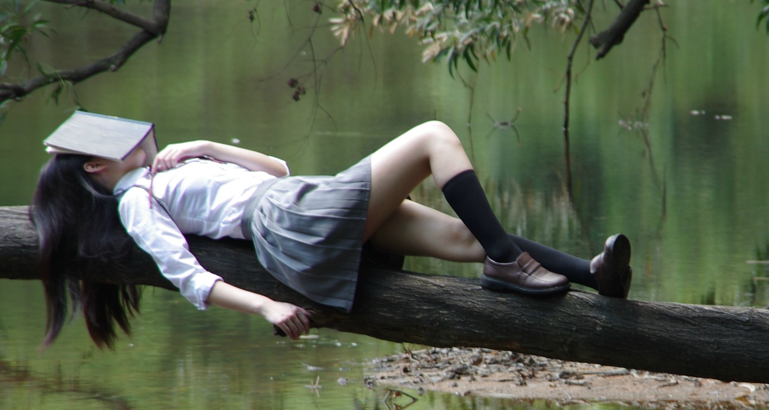 bored girl in school uniform on tree branch by lake