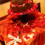 quinceañera decorations A beautiful Quinceanera cake with chocolate torte color and stunning red flower decorations on a table
