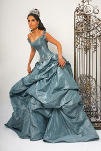 Quinceanera gown, a woman in a blue dress standing next to a bird cage