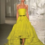 Quinceanera fashion model wearing a yellow gown walking down a runway