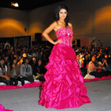 A woman in a pink Quinceanera dress standing in front of a crowd at a fashion show
