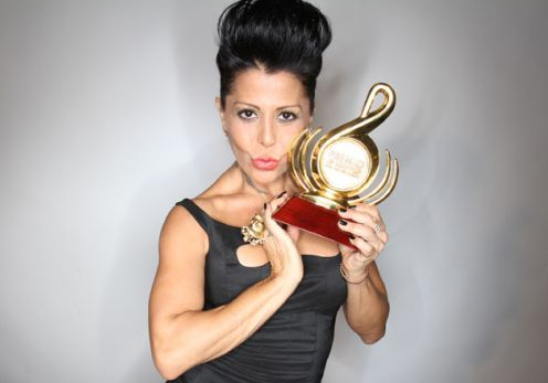 Alejandra Guzmán, a woman in a black dress holding a gold trophy at the Quinceanera awards