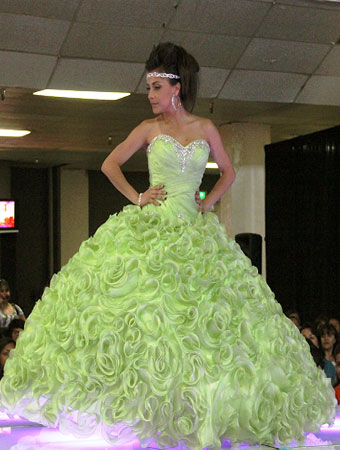 Quinceanera: A woman in a green gown walking down a runway.