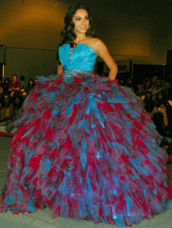 A woman in a blue and red Quinceanera gown walking down a runway