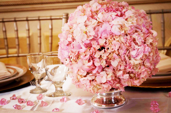 Table with Quinceanera-themed centerpiece decor, featuring a vase filled with pink flowers