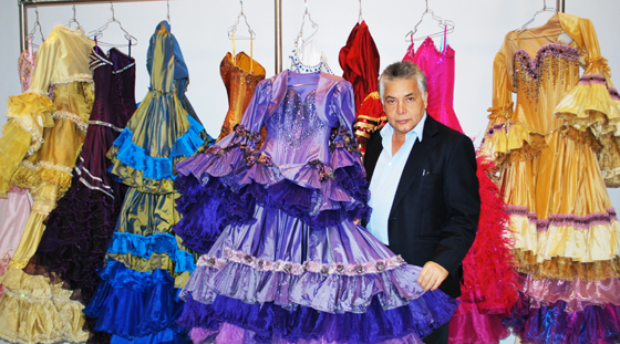 A man standing in front of a rack of Quinceañera dresses