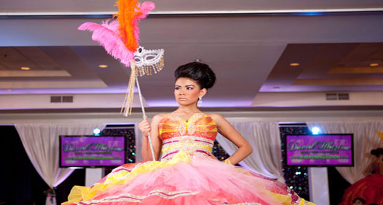 A woman in a colorful Quinceañera dress holding a feather at a Quinceañera carnival
