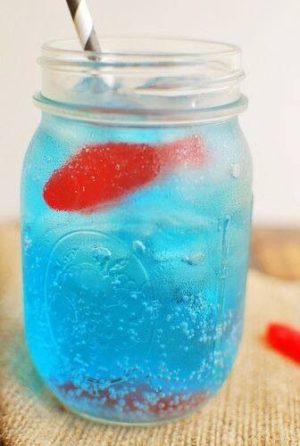 Blue Sprite with Swedish Fish, a blue drink with a red fish in it, perfect for Quinceanera celebrations.