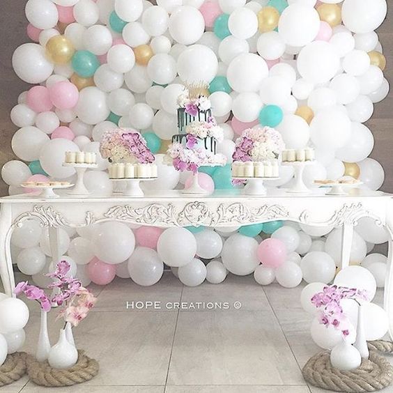 A shoulder Quinceañera standing near a table topped with a Quinceañera cake covered in pink and green paper fans
