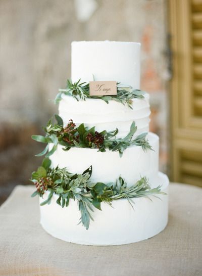 A three-tiered Quinceanera cake adorned with lush greenery