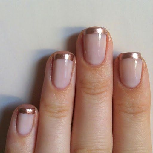 A woman's hand with a metallic French manicure in pink and gold
