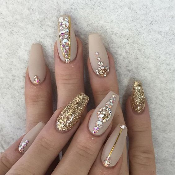 A Quinceanera-themed image of a woman's hand with a gold and white manicure, showcasing new year nail designs.