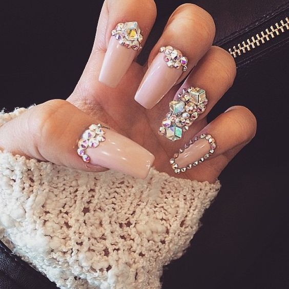 A person holding a pair of glammed up fake nails with rhinestones for Quinceanera