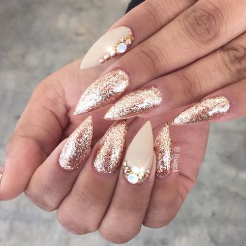 A person holding a gold and white manicure featuring nail art for a Quinceanera celebration