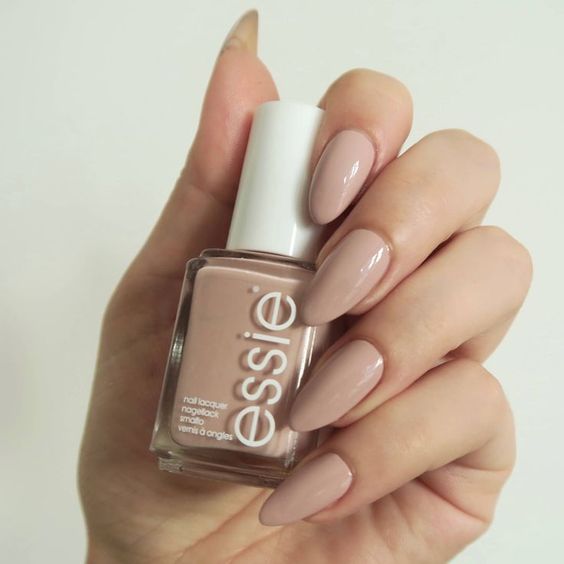 A person holding a bottle of Quinceanera-inspired nail polish in a nude color