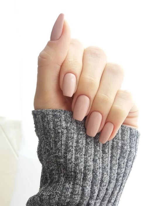 A woman's hand holding a pink Quinceanera manicure from lollis nail lacquer nude Nail Polish.