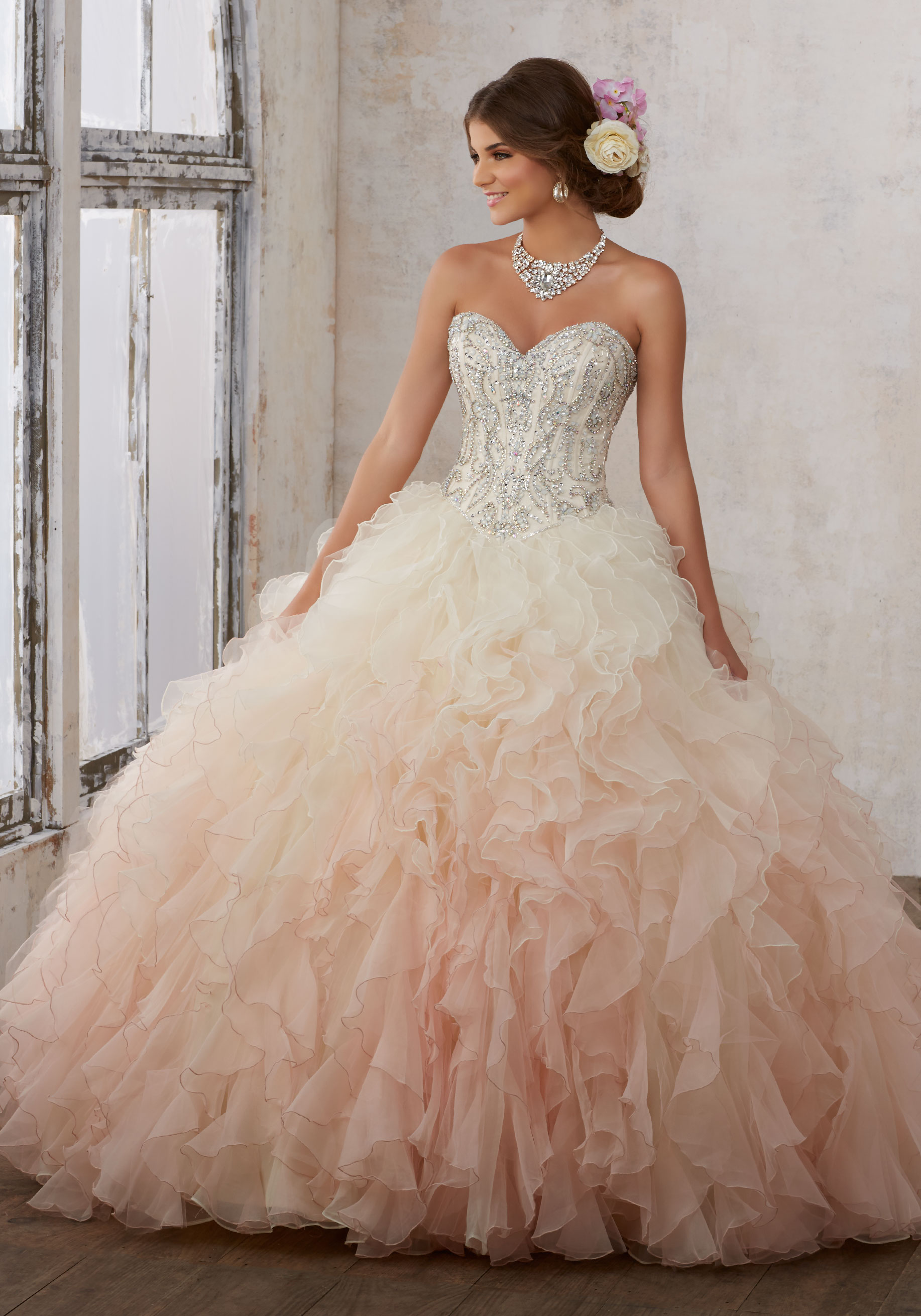 A woman in a pink ombre Quinceañera dress posing for a picture in a ball gown
