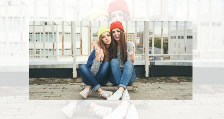 Two girls sitting on a skateboard having fun and being motivated about life
