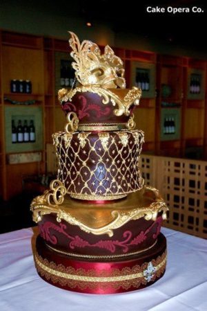 A quinceanera themed image featuring a masquerade theme. The image showcases a three-tiered cupcake with a dragon on top.
