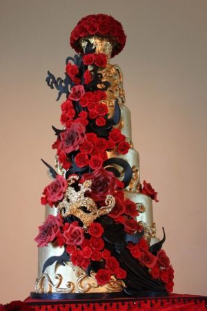 Red velvet quince cake adorned with red roses on top, featuring a stunning red, black, and gold color scheme