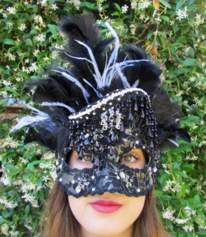 A woman wearing a black and white mask and a masque headpiece for a Quinceanera celebration.