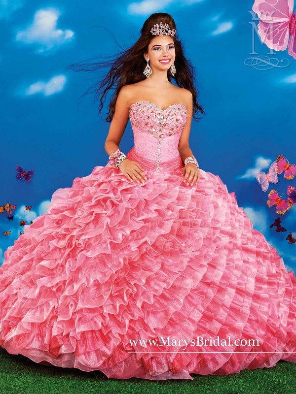 A woman in a pink gown Quinceañera dress posing for a picture
