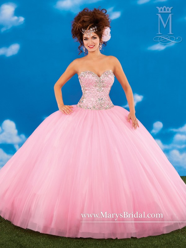 A woman in a pink ball gown posing for a picture at a Quinceanera