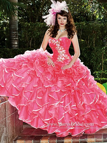 A woman in a pink ball gown posing for a picture at a Quinceanera