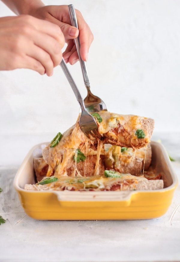 A person is cutting into a Quinceanera casserole dish filled with enchiladas de pollo ingredients
