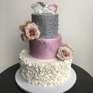 A three tiered Quinceanera cake with pink and silver decorations