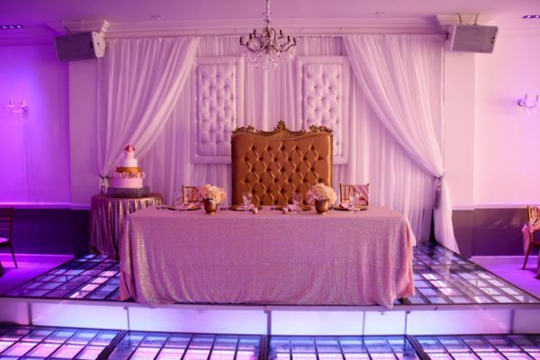 A Quinceanera-themed function hall table with a large bed sitting on top of a purple floor