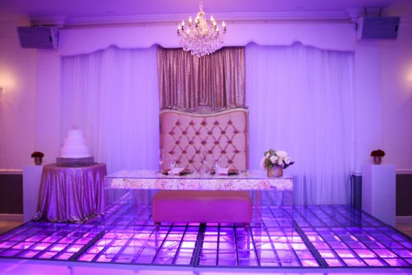 A Quinceanera function hall table with a purple and white reception setup and a chandelier.