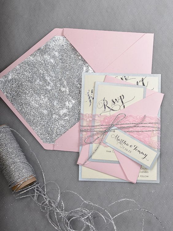 A pink and silver Quinceanera invitation made of paper with a ribbon