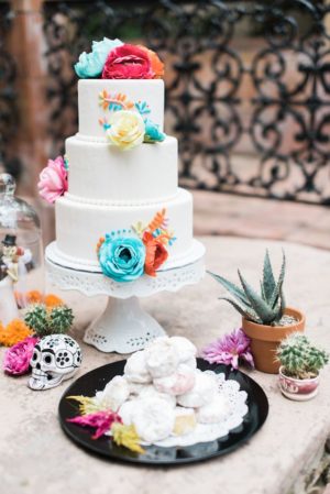 Quinceanera cake decorated with colorful flowers on a table, inspired by Day of the Dead