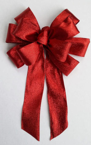 A Quinceanera themed image featuring a ribbon Christmas decoration and a red bow on a white surface