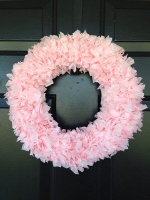 A Quinceanera-themed wreath Christmas decoration hanging on a black door, featuring a pink wreath.