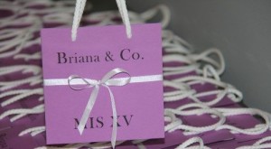 A beautiful lilac gift bag with a white ribbon tied to it, perfect for a Quinceanera celebration.