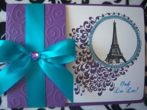 A close up of a card with a bow as a decoration for a Quinceanera celebration with a torre eiffel de Paris theme