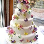 A three tiered Quinceanera cake decorated with flowers and butterflies.