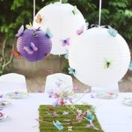 A Quinceanera party with a table topped with lots of white paper lanterns and butterfly decorations