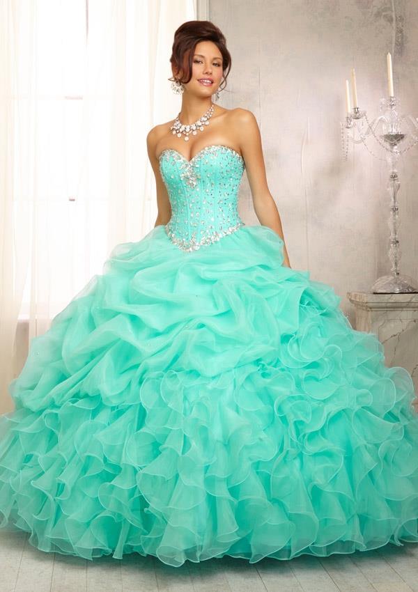 A woman in a teal sweet 16 Quinceañera dress posing for a picture