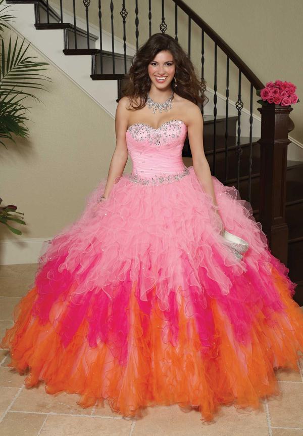 Quinceañera dresses, a woman in a pink and orange dress posing for a picture during sunset