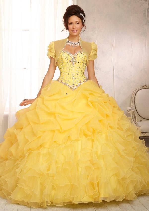 A woman in a yellow Quinceanera dress poses for a picture at a Quinceanera event