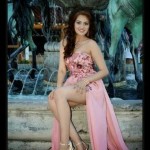 A beautiful woman in a pink dress sitting in front of a fountain, showcasing Quinceanera fashion